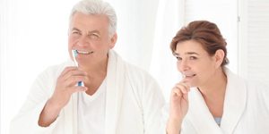 Older man and woman brushing teeth
